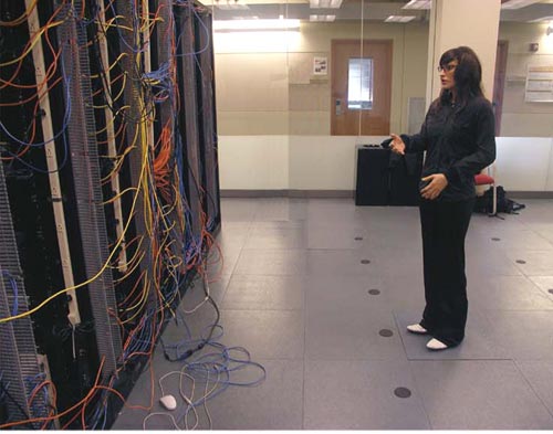 Person inspecting server racks with tangled cables